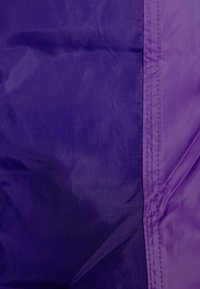 Tissu violet à la texture lisse et brillante, présentant une couture le long du bord gauche et des variations subtiles de couleur.