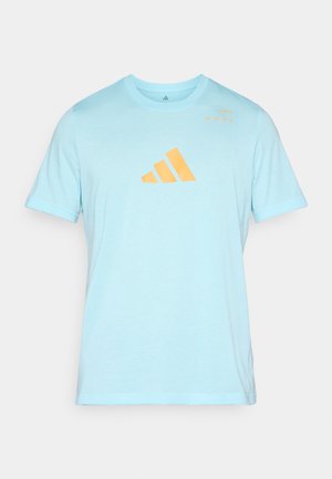Light blue short-sleeve t-shirt made of soft fabric. Features an orange adidas logo graphic on the front and minimal text detail.