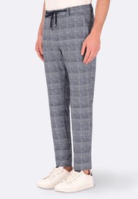 Pantaloni grigi da uomo con motivo, realizzati in tessuto leggero, con vita regolabile e vestibilità affusolata, abbinati a sneaker bianche.