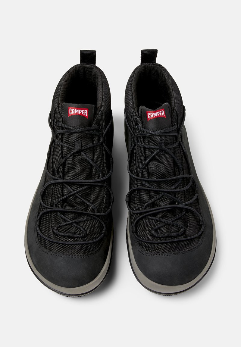 Schwarze High-Top-Schuhe mit Netzdetails und elastischen Schnürsenkeln, mit einem roten CAMPER-Logo auf der Zunge.