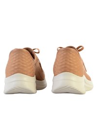 Zapatillas deportivas de color rosa claro con un upper texturizado con un patrón de diamantes, suela acolchada blanca y cierre de cordones en la parte trasera.
