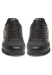 Crne sintetičke tenisice sa zlatnim detaljima, zaobljenim vrhom, kontrastnim teksturama i teksturiranim potplatom. Vezice su provučene kroz tkaninske okice.