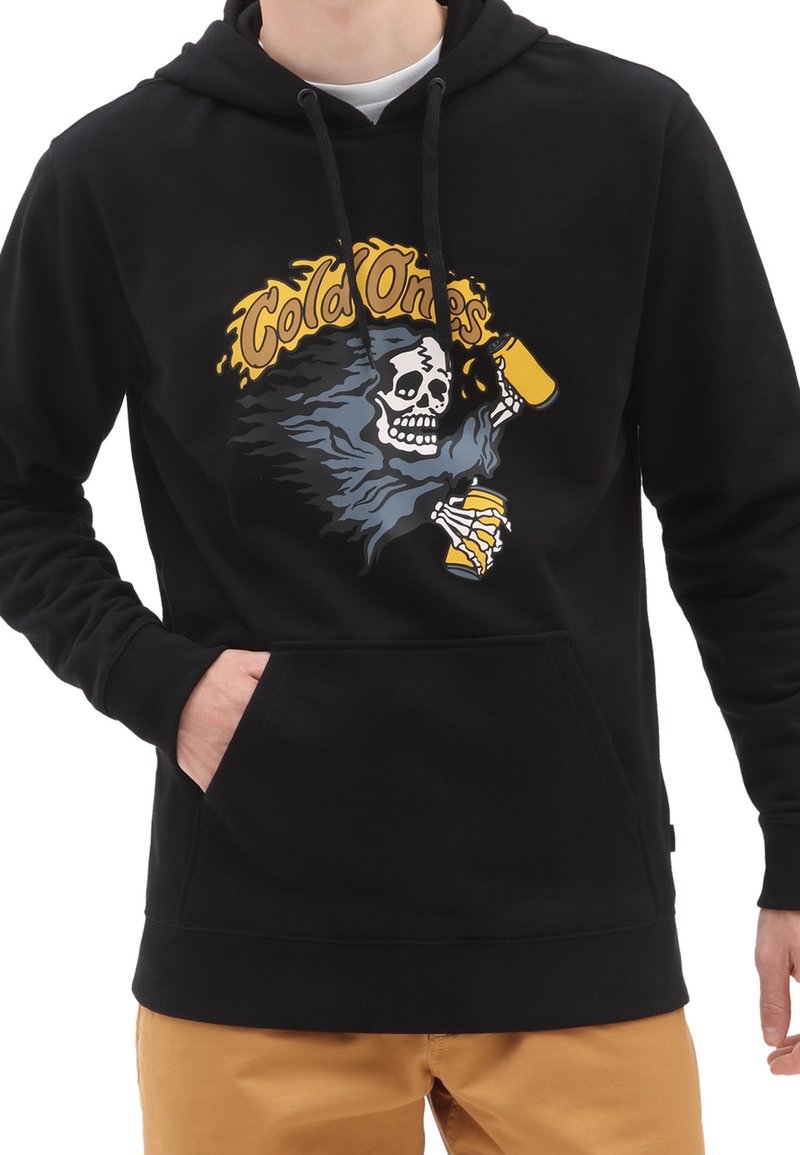 Homme portant un sweat à capuche noir avec un graphique d’un squelette tenant deux canettes jaunes et le texte "Cold Ones" en jaune au-dessus.