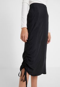 Svart satin midikjol med veckade sid sömmar, justerbara band vid fållen, slät textur och en elegant silhuett.