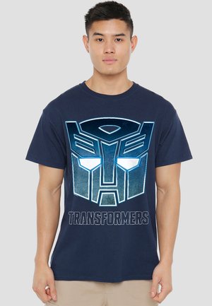 Marineblaues Baumwoll-T-Shirt mit großem Transformers-Logo-Graphic in Blau und Silber, mit dem Schriftzug "TRANSFORMERS" darunter. Kurze Ärmel.
