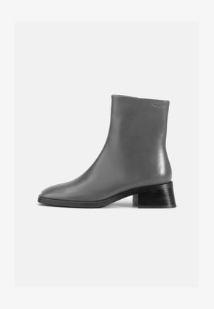 Bota de tornozelo em couro cinza com bico arredondado e um tacão preto curto e empilhado. Textura lisa com detalhes mínimos.
