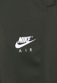 Pantalones cortos verdes de Nike hechos de una tela suave, con un logo blanco que dice "NIKE AIR" exhibido de manera prominente.
