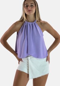 Paarse haltertop met draperend ontwerp en gathered halslijn; gecombineerd met witte asymmetrische denimshorts met een rafelige zoom.