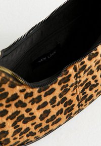 Pouch w panterkę z miękkim, teksturowanym, jasnobrązowym wykończeniem i czarnymi akcentami. Wyposażona w zamek błyskawiczny oraz czarne, wyłożone wnętrze.