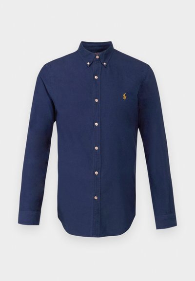 Camisa de manga longa azul-marinho feita de algodão, com colarinho abotoado e um pequeno logótipo dourado no peito. Corte clássico com pala de botões.