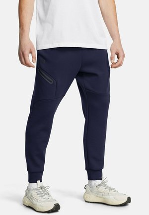 Navy sweatpants feature a tapered design, side zip pockets, and ribbed cuffs, made from a soft, stretchy material for comfort and mobility.