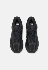 Černé sportovní boty z prodyšné síťoviny a syntetických materiálů, s kulatou podrážkou, tradičním šněrováním a texturovanými detaily na svršku.