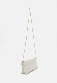 Krämfärgad konstläderhandväska med en triangulär klaff, guldkedjestrap och en strukturerad design, som har en slät yta och en minimalistisk stil.