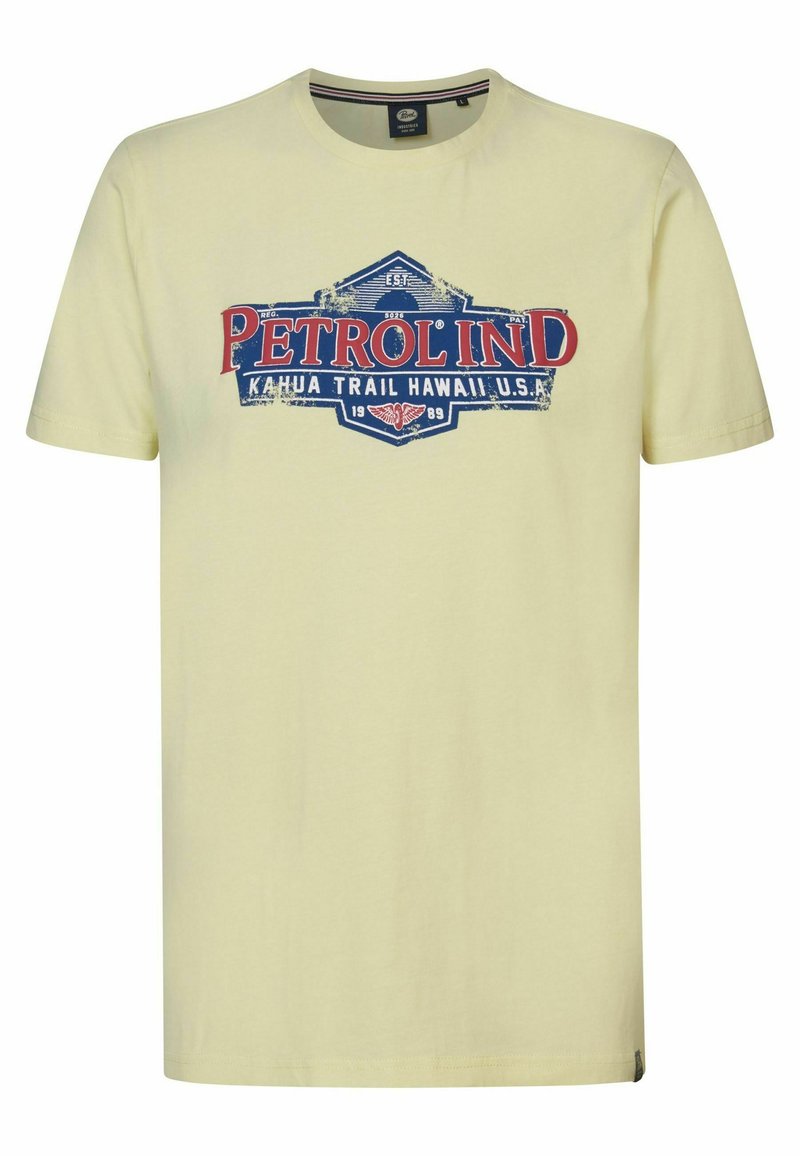 Světle žluté bavlněné tričko s grafickým potiskem "PETROL IND" v červené a modré barvě, umístěné na vintage stylovém designu štítku.