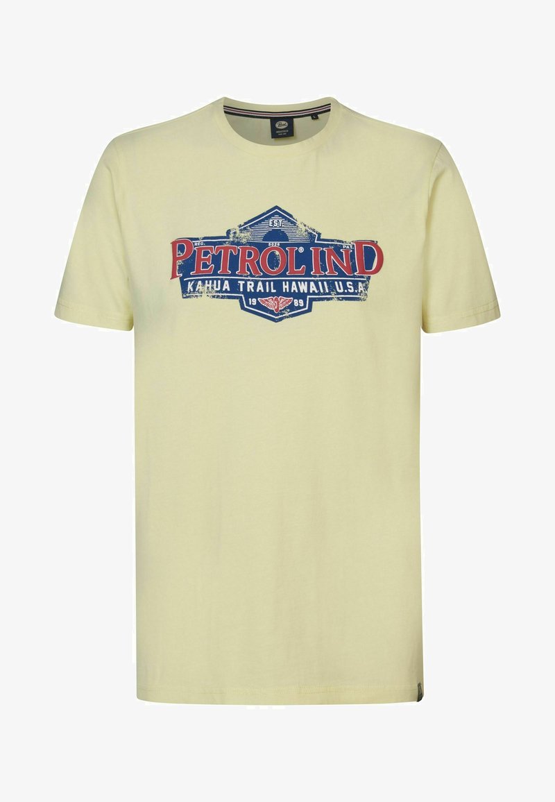 Světle žluté bavlněné tričko s grafickým potiskem "PETROL IND" v červené a modré barvě, umístěné na vintage stylovém designu štítku.