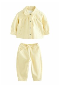Veste rayée jaune avec un col et des boutons-pression, associée à un pantalon rayé assorti avec une taille élastique et des poches.