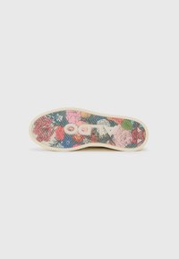 Semelle de chaussure avec un bord beige clair, motif floral coloré en rose, bleu et vert sur un fond texturé. Logo ALDO visible.