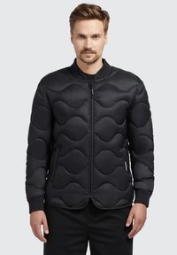 Black padded jacket featuring a wave pattern, zip closure, ribbed cuffs, and a round collar, made of smooth, water-resistant fabric.