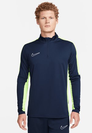 Marineblauw lange mouw sporttop met ritssluiting, met helder groene zijpanelen en een wit Nike logo op de borst. Rekbaar materiaal.