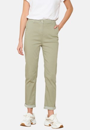 Light green cotton trousers featuring a high waist, straight leg, and rolled cuffs, paired with white sneakers and a plain white shirt.