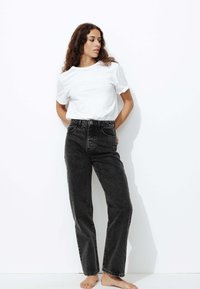 Jean droit noir à taille haute avec un design à cinq poches, associé à un t-shirt blanc uni à manches courtes.