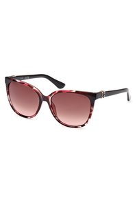 Lunettes de soleil avec une monture en forme d'œil de chat dans un motif marbré bordeaux et noir. Verres dégradés marron avec un accent métallique sur la branche.