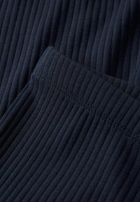 Donker marineblauwe ribstof met een zachte textuur, met een zichtbare elastische tailleband en een gladde naad, die de rekbaarheid benadrukt.