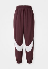 Marron joggebukser med et hvitt buet stripe-design, elastisk midjebånd og smale cuffs. Laget av lett, pustende materiale.