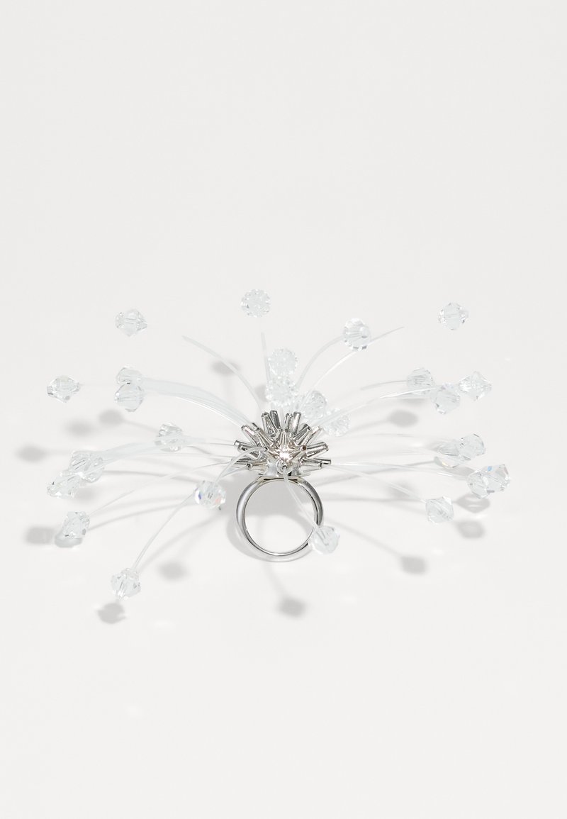 Sølv ring med transparente plasttråde og flere klare krystalliske accenter, der ligner et blomst- eller stjerneburst design.