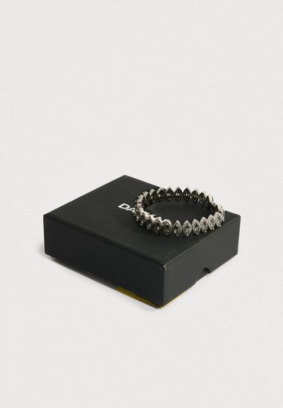 Ezüst színű karkötő, fekete, marquise alakú kövekkel, fekete dobozon, részlegesen fehér szöveggel, egyszerű világos háttéren.