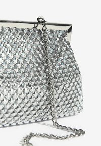 Geantă de mână argintie cu o suprafață texturată, decorată cu forme de diamant, un cadru metalic și o curea din lanț argintiu.