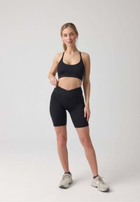 Zwart sportset bestaande uit een aangesloten crop top en high-waisted biker shorts. Gladde textuur en minimale naden, ideaal voor sportkleding.