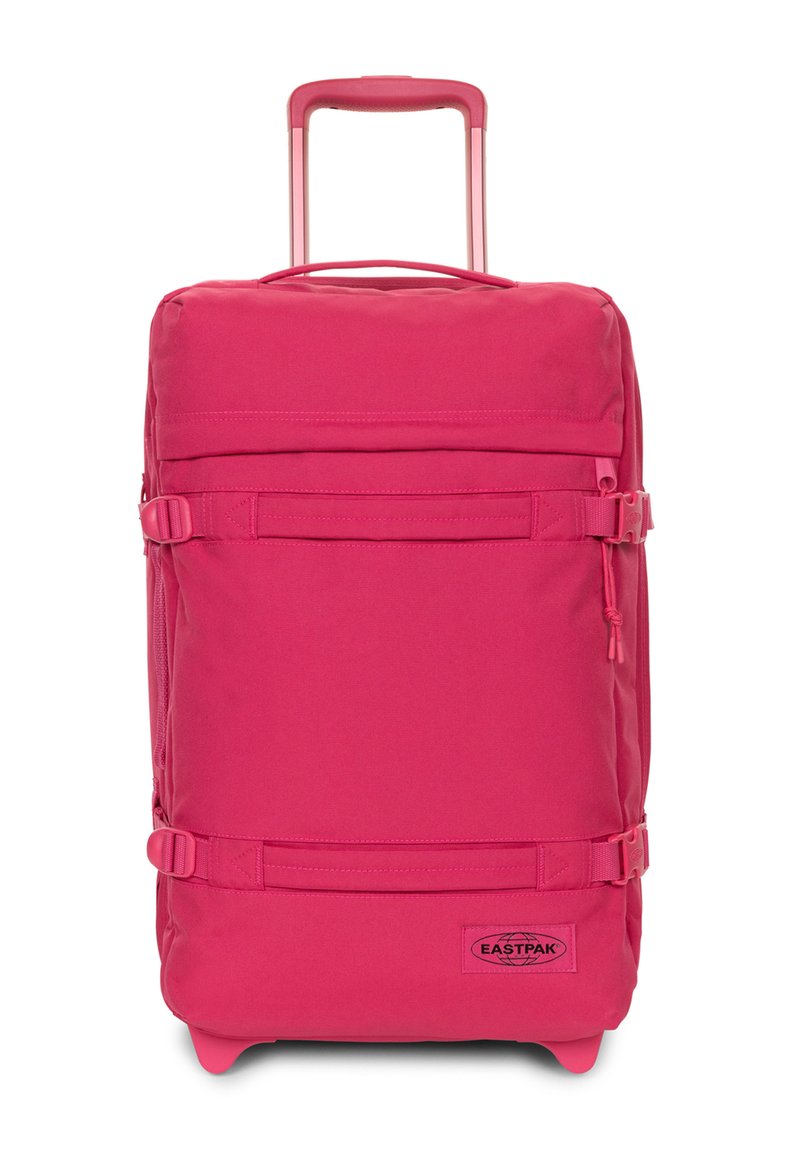 Valigia morbida rosa con manico retrattile, cinghie laterali, tessuto resistente e una toppa con logo nella parte inferiore.