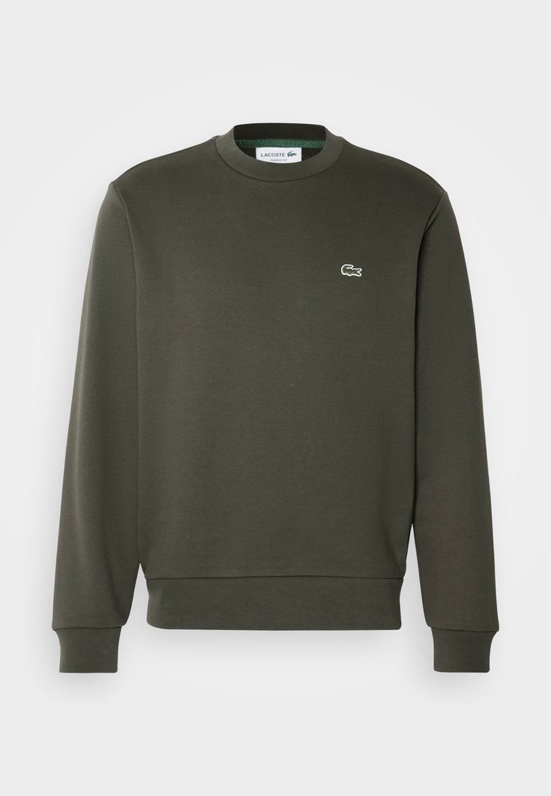 Sweat-shirt vert foncé en tissu doux, avec un col rond et des manches longues. Présente un petit logo brodé blanc sur la poitrine.