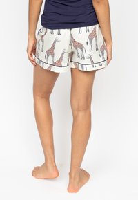 Korte broek met giraffepatroon in crème met marineblauwe accenten. Lichtgewicht stof, ontspannen pasvorm, elastische tailleband en zichtbare zakken.