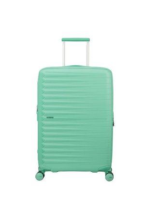 Valigia rigida turchese con scanalature orizzontali, manico estensibile e quattro ruote girevoli, posizionata in verticale su sfondo bianco.