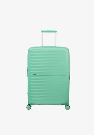 Valigia rigida turchese con scanalature orizzontali, manico estensibile e quattro ruote girevoli, posizionata in verticale su sfondo bianco.