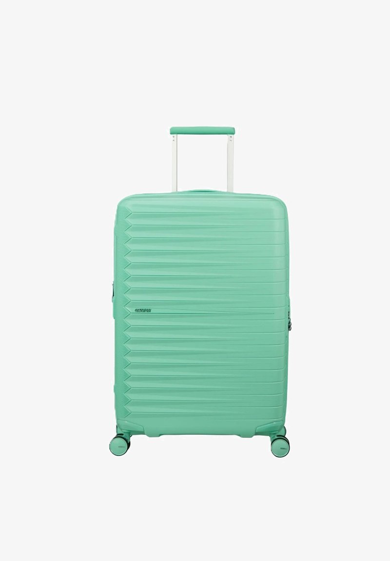 Valigia rigida turchese con scanalature orizzontali, manico estensibile e quattro ruote girevoli, posizionata in verticale su sfondo bianco.