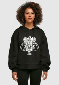 Svart oversized hoodie med en vit grafisk design som har intrikata detaljer och ribbad nederkant. Materialet verkar mjukt och texturerat.
