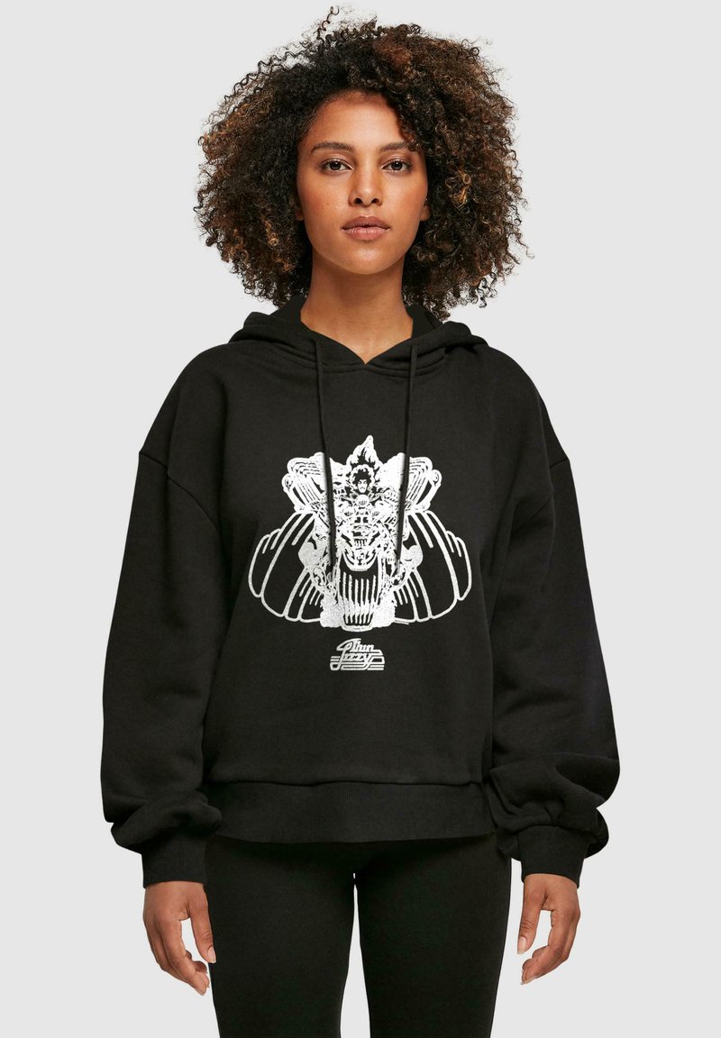 Svart oversized hoodie med en vit grafisk design som har intrikata detaljer och ribbad nederkant. Materialet verkar mjukt och texturerat.
