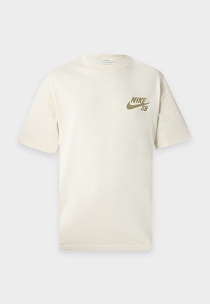 T-shirt Nike SB beige clair uni à manches courtes avec col rond et petit logo Nike marron sur le côté gauche de la poitrine.
