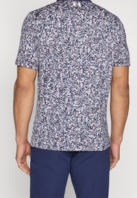 Kortärmad skjorta med en marinblå bakgrund, prydd med ett blommönster i rosa och ljusblå nyanser. Tillverkad av ett lätt tyg.