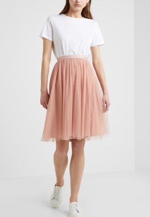 Lyserød tylnederdel med prikker, elastisk talje, parret med en hvid t-shirt med rund hals og hvide sneakers.