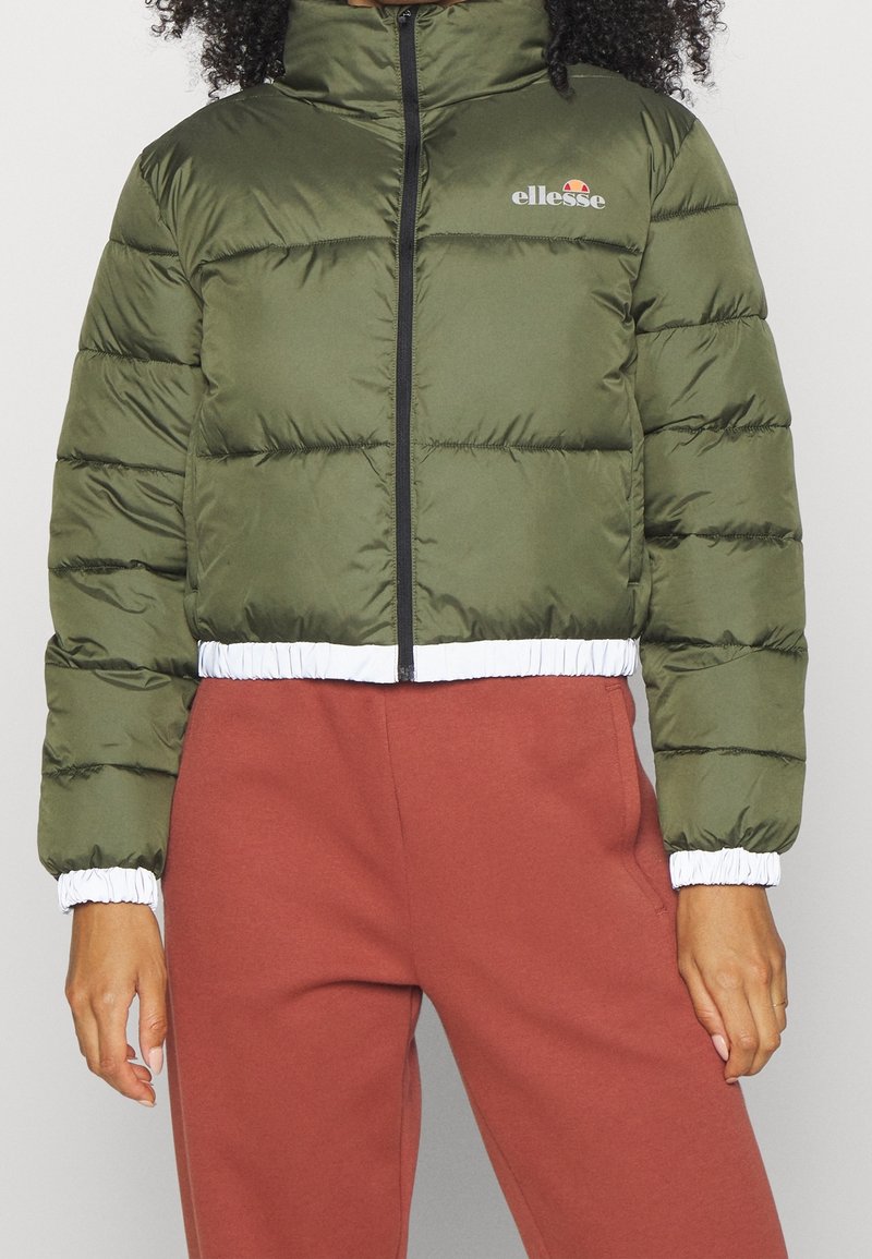 Giubbotto imbottito verde con zip nera, polsini elastici e orlo bianco. Presenta il logo sul petto. Silhouette cropped e superficie liscia.