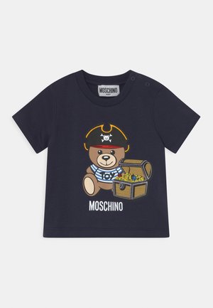T-shirt per bambini col colore navy con un orsetto sorridente che indossa un cappello da pirata e una maglietta a righe, seduto accanto a un tesoro aperto, con il testo "Moschino" sottostante.