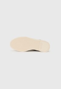 Rubber shoe sole with a textured pattern; beige color with a smooth finish. Features a rectangular logo on the side.