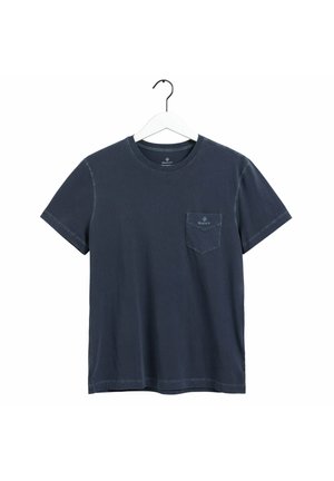 Granatowy t-shirt z krótkimi rękawami i okrągłym dekoltem, z logo na kieszeni na piersi, wiszący na białym wieszaku na białym tle.