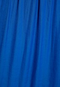 Tessuto blu brillante con una texture liscia e una leggera lucentezza, caratterizzato da pieghe morbide che creano un aspetto fluido.