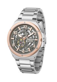 Reloj de acero inoxidable plateado con un bisel de oro rosa, esfera esqueleto y grandes números. Presenta intrincados engranajes y una pulsera de eslabones metálicos.