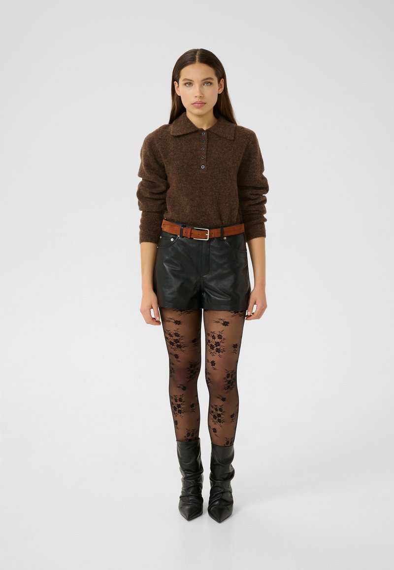 Brown knit sweater with a collar and buttons, paired with black leather shorts, sheer floral tights, and knee-high black boots.
